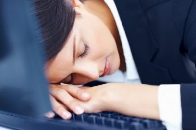 Tired young business woman sleeping on computer keyboard